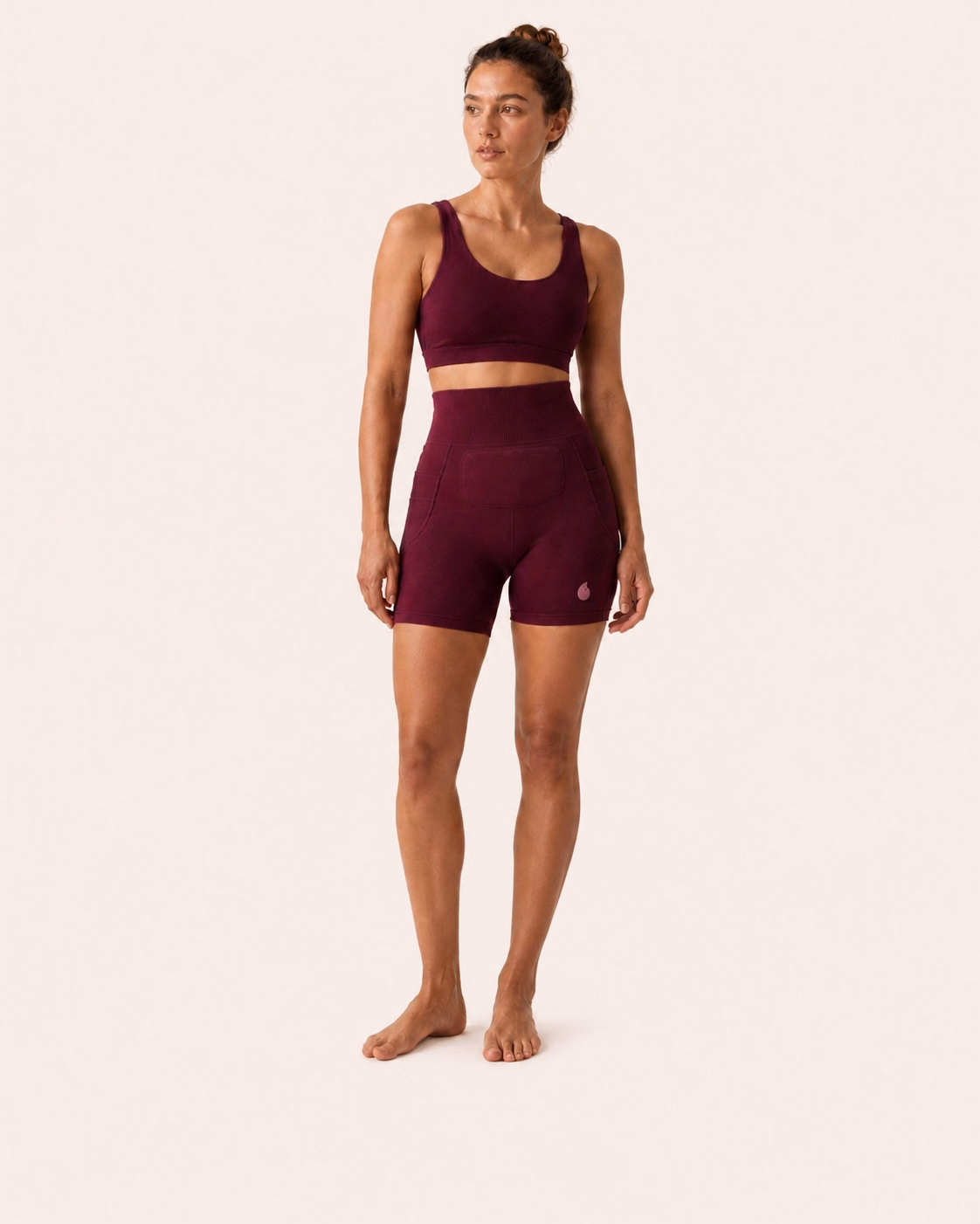 Une femme porte le short Simone en coloris Bordeaux sur un fond studio ivoire uniforme.