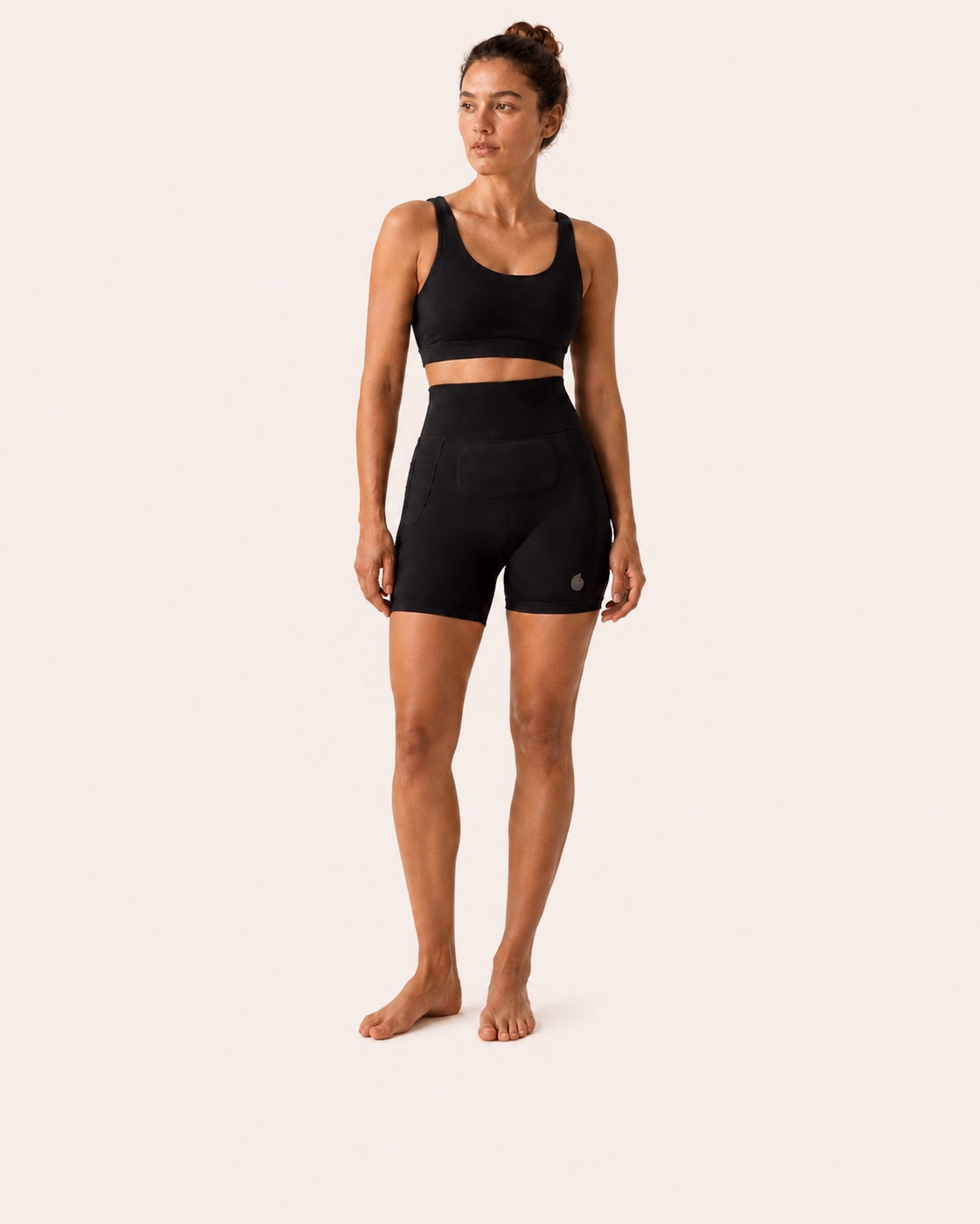 Une femme porte le short Simone en coloris Noir sur un fond studio ivoire uniforme.